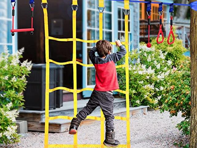 A child working up the yellow ninja line cargo net in a backyard